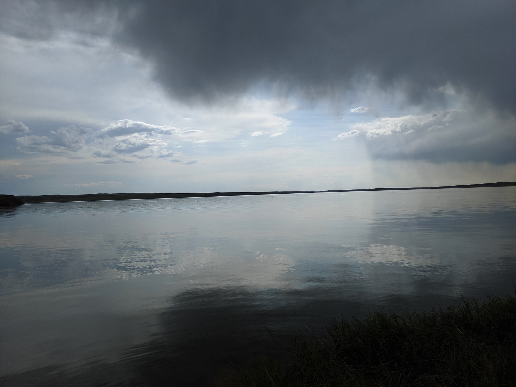 clouds over a perfectly flat lake with their reflection creating a perfect circle.