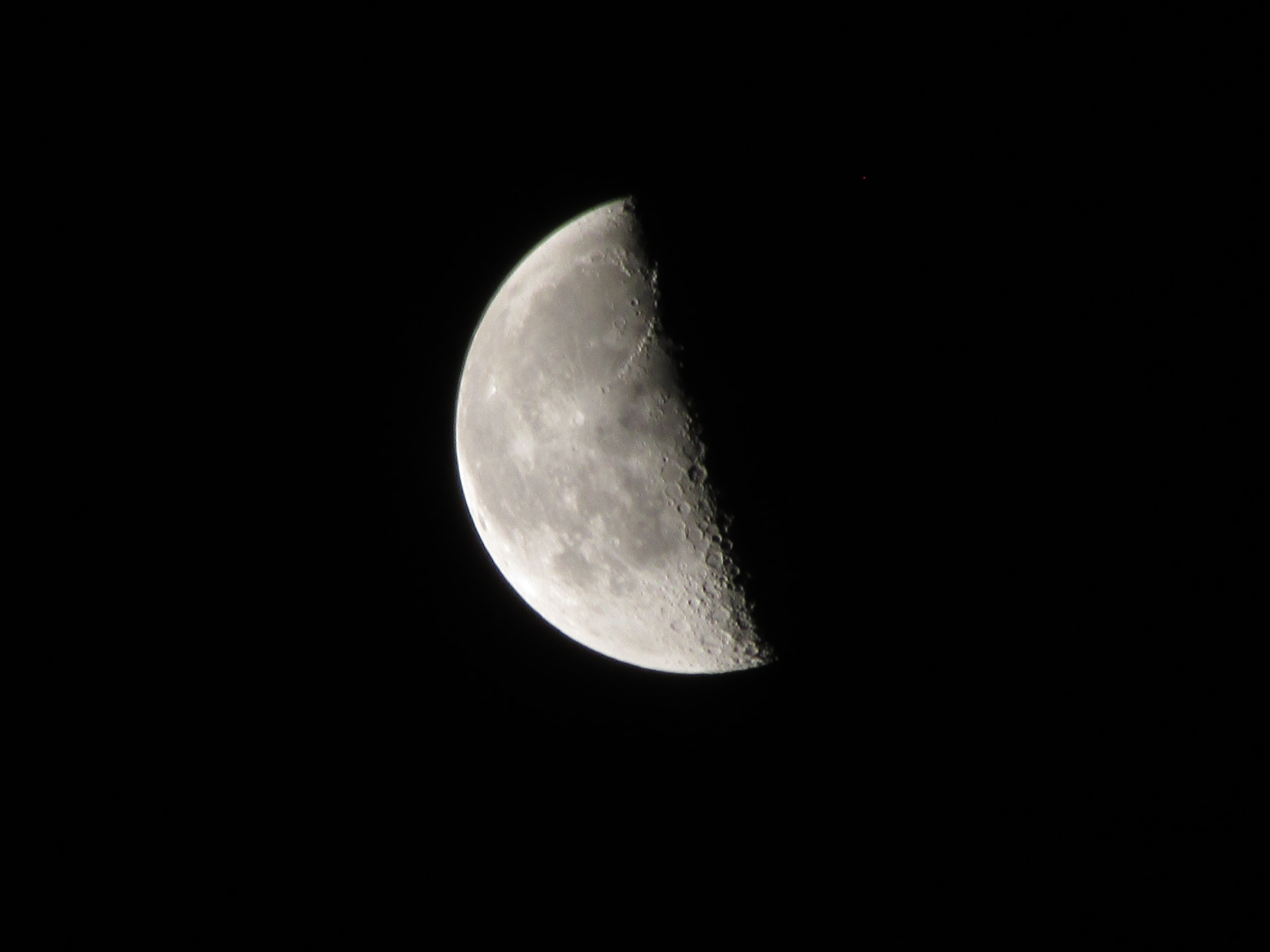 a white moon on a black sky. the craters on the moon are visible.